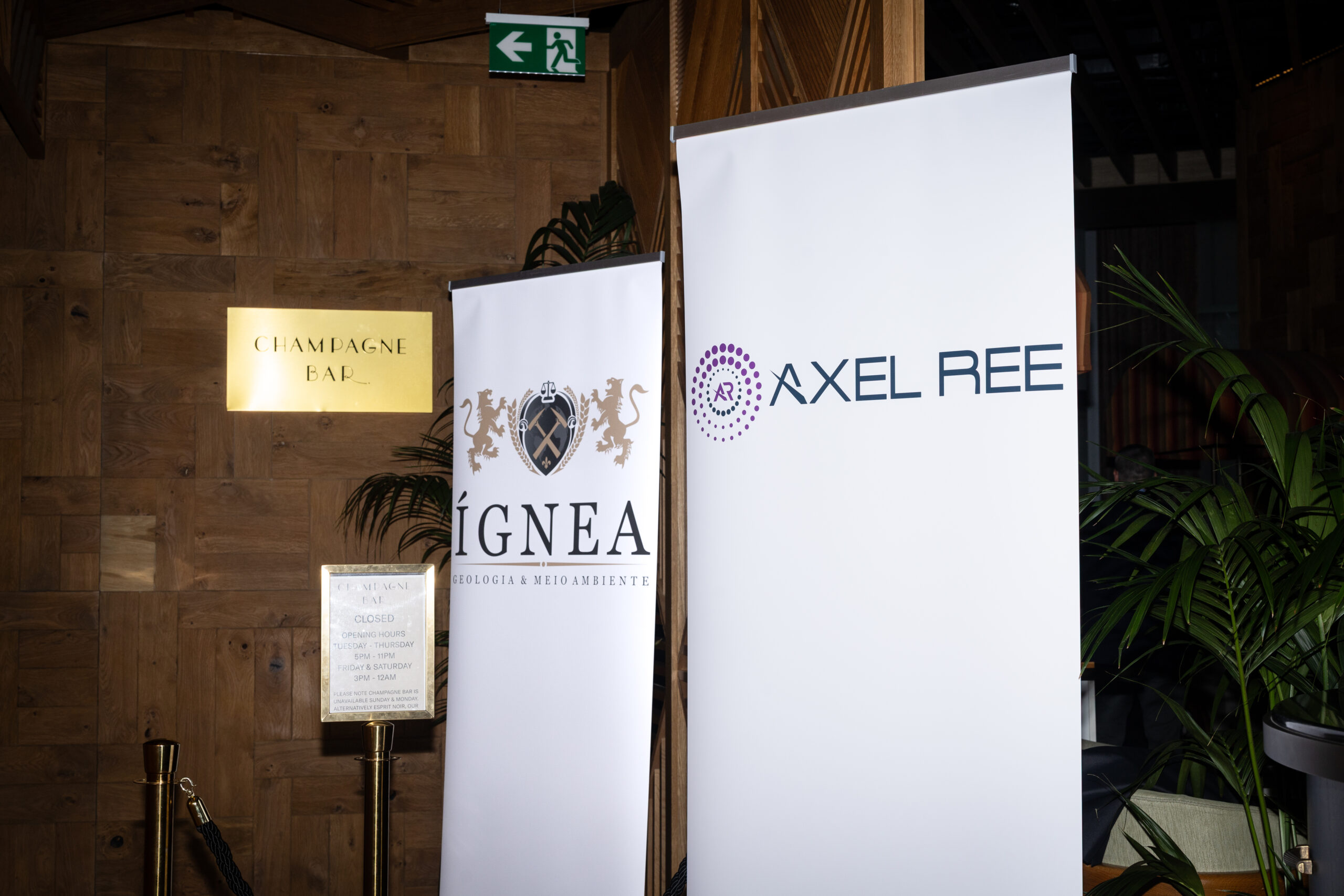 Banners da Ígnea e da Axel REE ao lado da placa do Champagne Bar, no evento em Sydney.