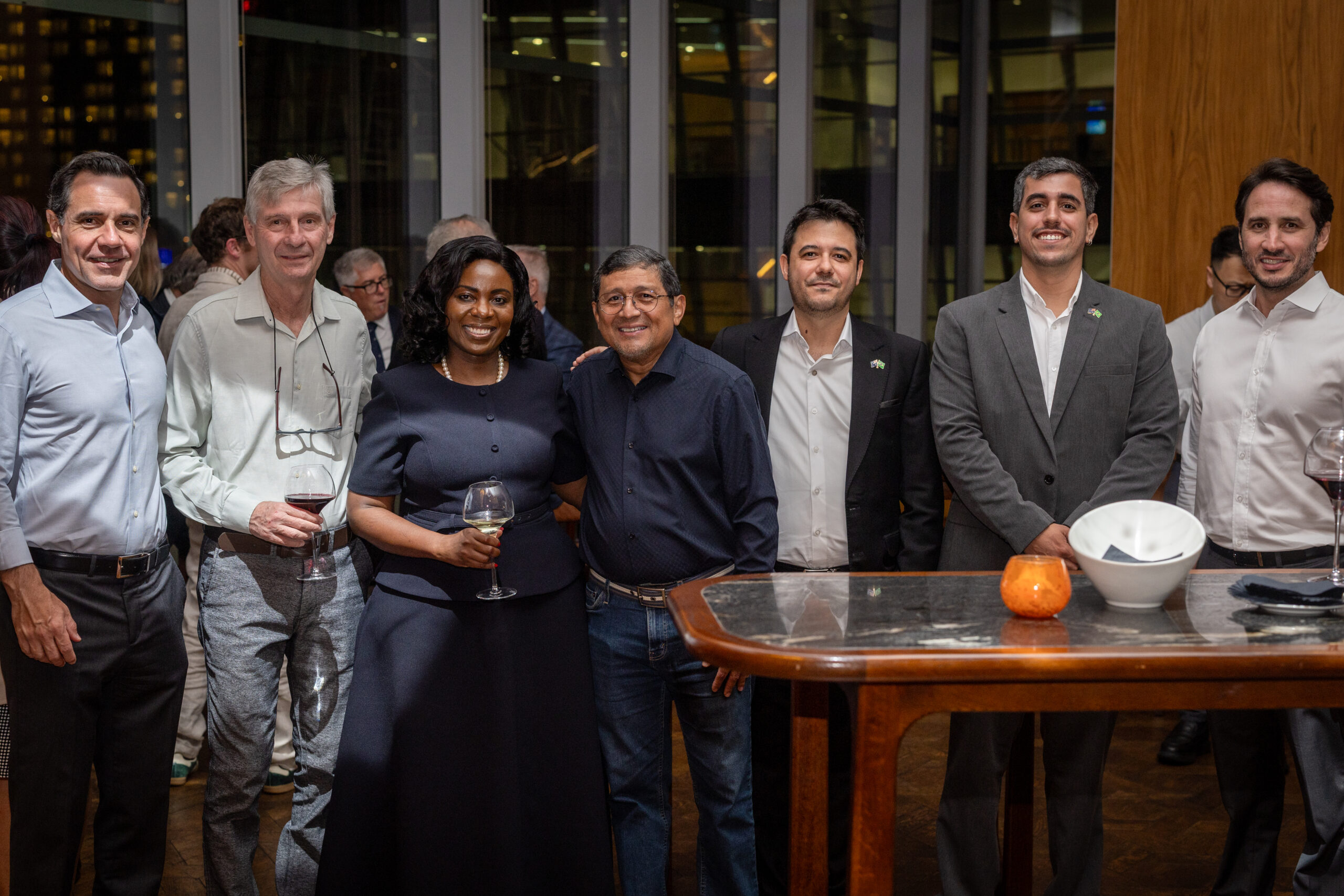 Grupo de sete pessoas posando junto a uma mesa alta durante o encontro, em Sydney.